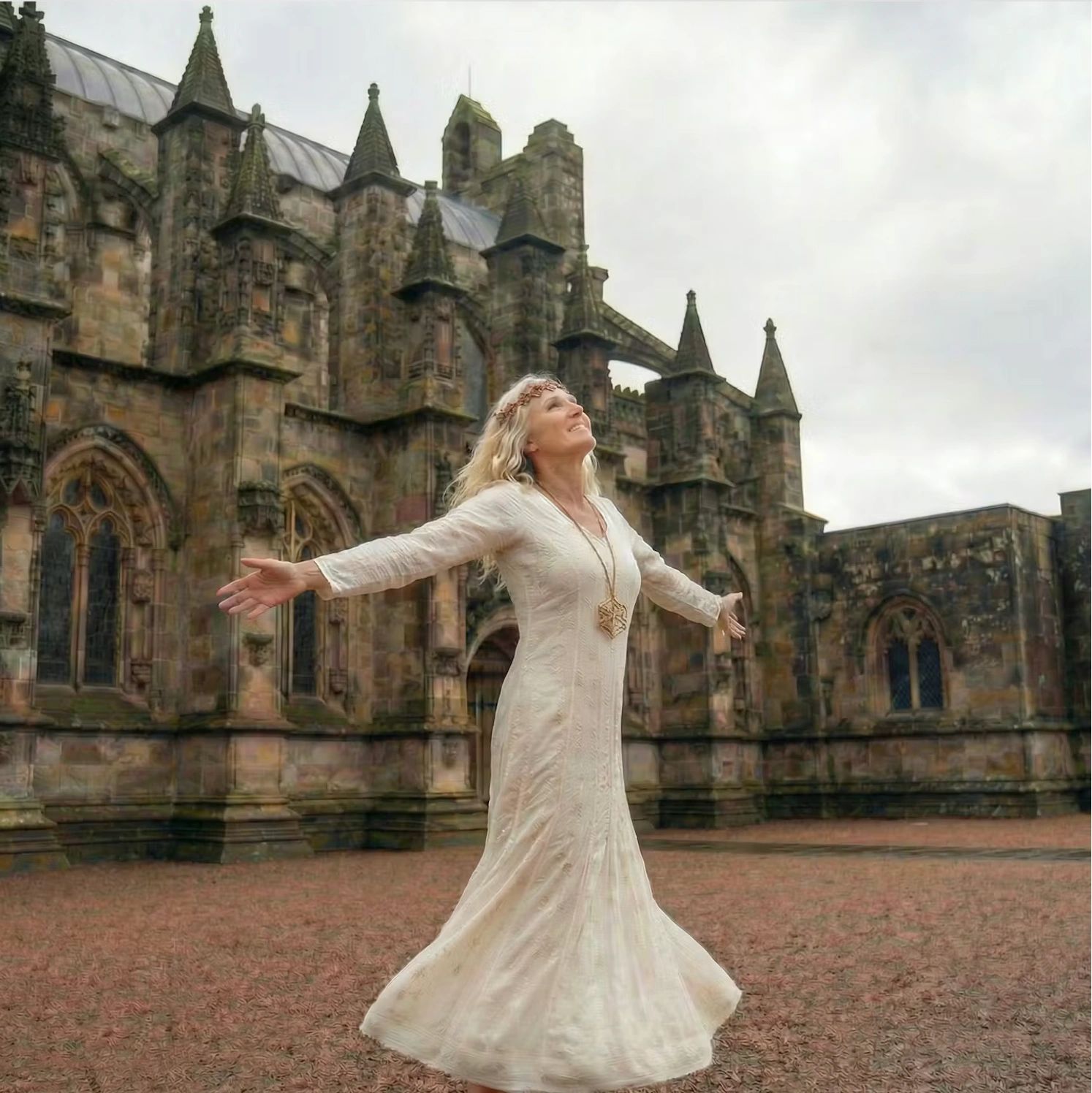 Practitioner standing with open arms before gothic cathedral architecture